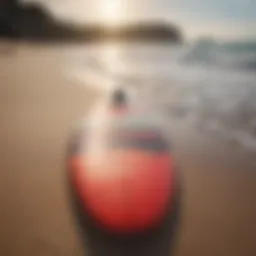 A vibrant soft top long surfboard resting on the sandy beach with gentle waves in the background.