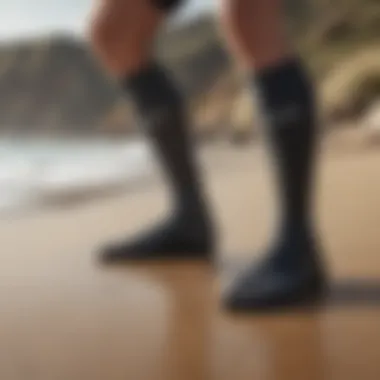 A pair of high-performance wetsuit socks on a sandy beach