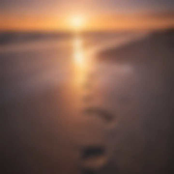 Sunset over tranquil beach with footprints in the sand