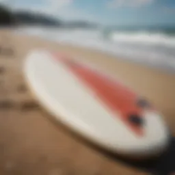 A sleek mid-length surfboard resting on the beach with waves in the background.